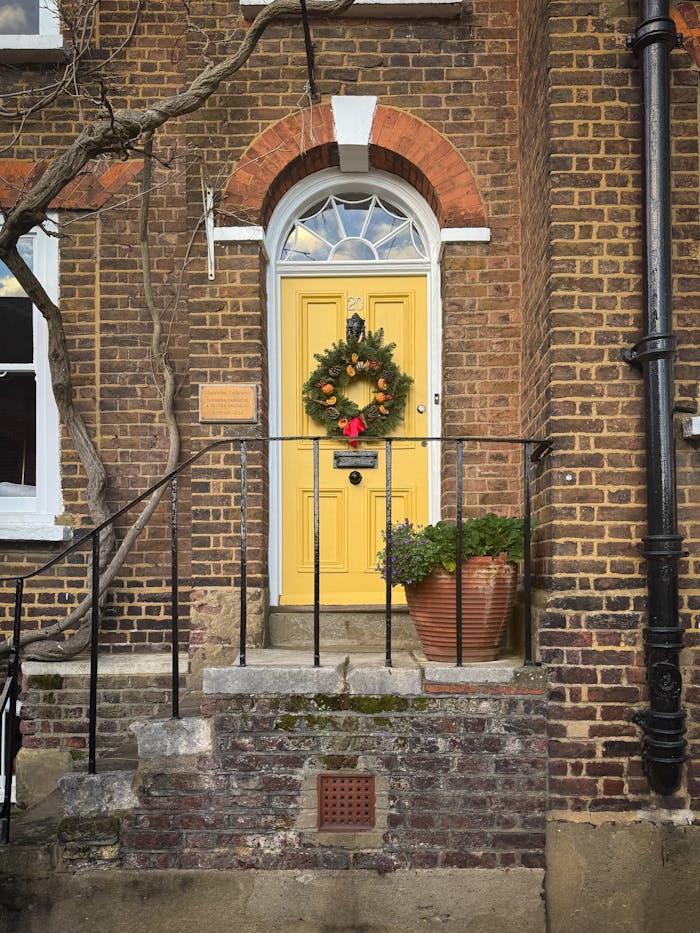 Brick house with yellow door and holiday wreath in Hampstead, London.