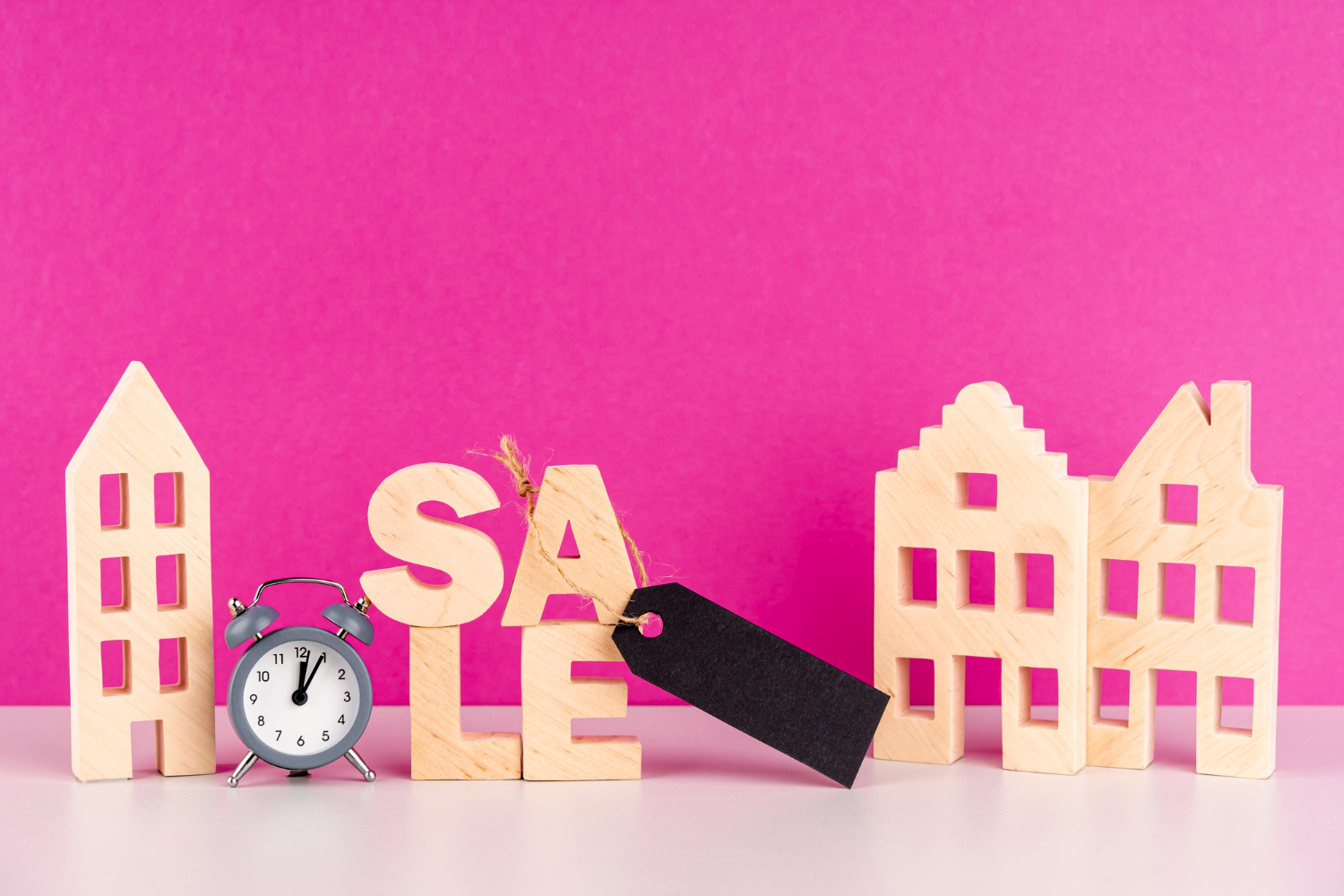 Wooden blocks spelling "SALE" on a vibrant pink background, emphasising a promotional message